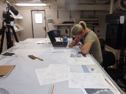 Cathy Green transfers underwater drawings and measurements to a scaled shipwreck site plan.