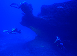 Technical divers working along a ledge at 220-240 feet at Pearl and Hermes Atoll, Papahānaumokuākea Marine National Monument.