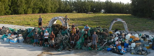 Workers stand in front of piles of marine debris collected in Papahānaumokuākea.