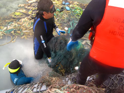 Workers remove loads of marine debris from shallow reefs in Papahānaumokuākea.