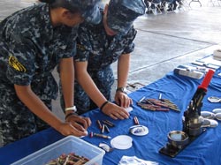 U.S. Naval Officers making buttons at the Papahānaumokuākea outreach table.