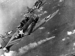 SBD Dauntless dive bombers from USS Hornet approaching the burning Japanese heavy cruiser Mikuma.