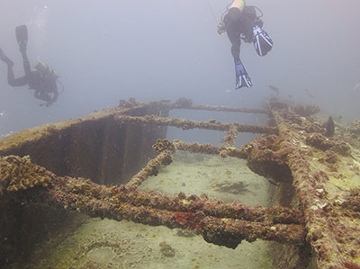 Divers swim over the hull structure of USNS <em>Mission San Miguel</em>.
