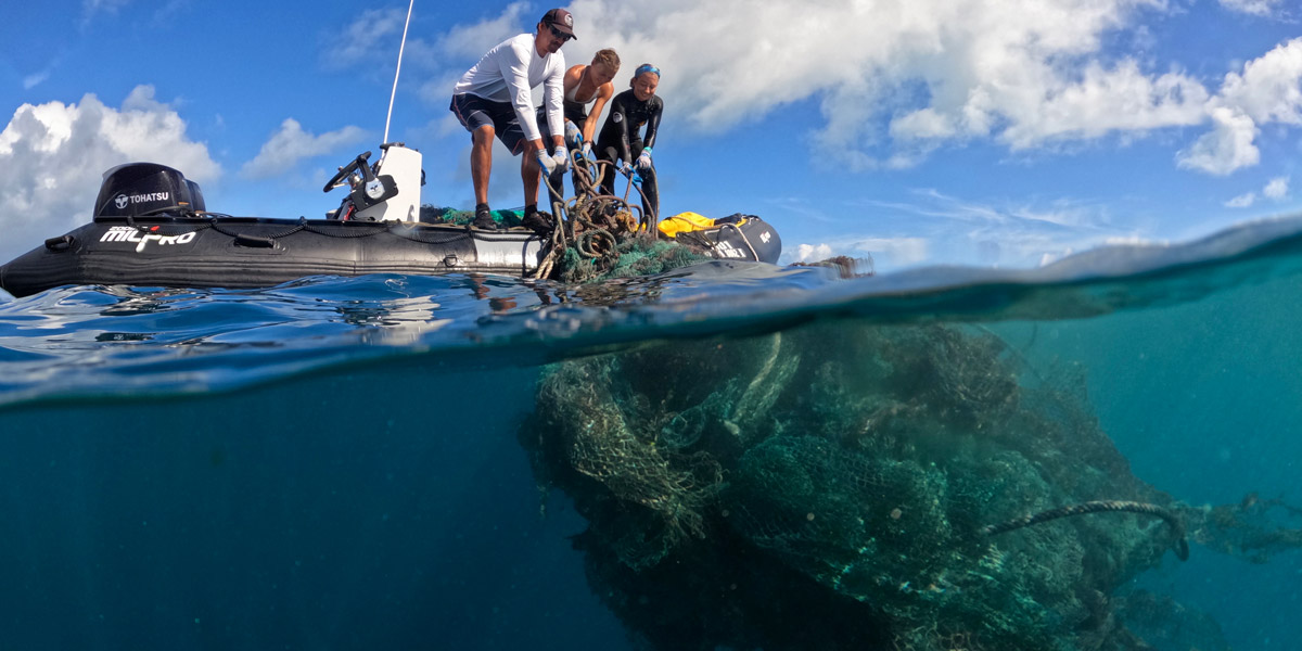 Divers haul large nets into their boat.