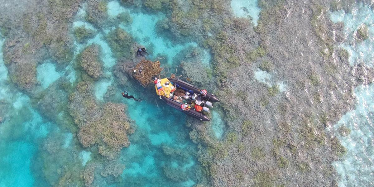 Aerial view of divers collecting marine debris along shallow reef.