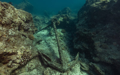 Anchor on seafloor alongside reef.