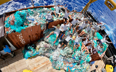 Marine debris team sitting on large piles of marine debris on the ship.