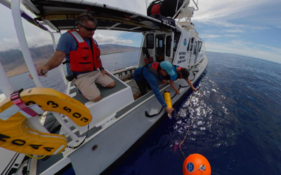 Researchers deploy an acoustic mooring from small boat.
